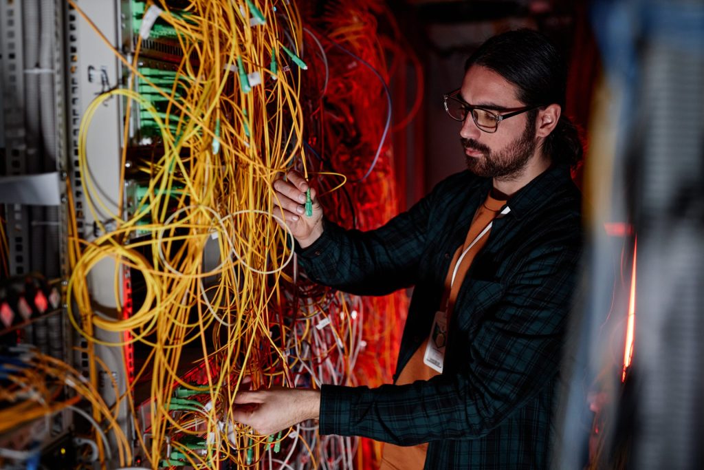Seitenansicht eines bärtigen Mannes als Systemadministrator, der das Servernetzwerk einrichtet und Wartungsarbeiten durchführt.