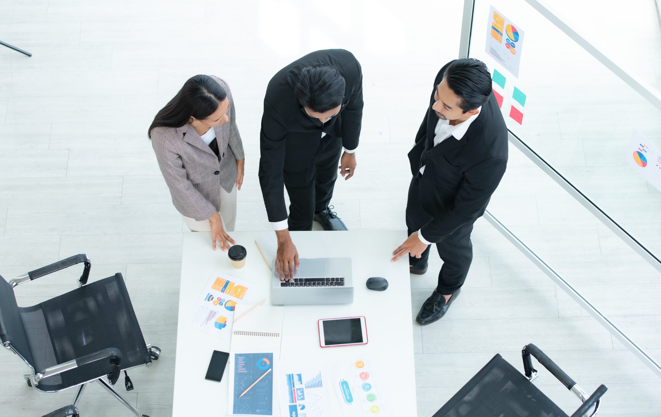 Eine Gruppe junger asiatischer Unternehmer. Das Top-Management trifft sich, um die Aktieninvestitionsdaten des Teams in einem Besprechungsraum mit Fenstern und natürlichem Licht zu überprüfen.