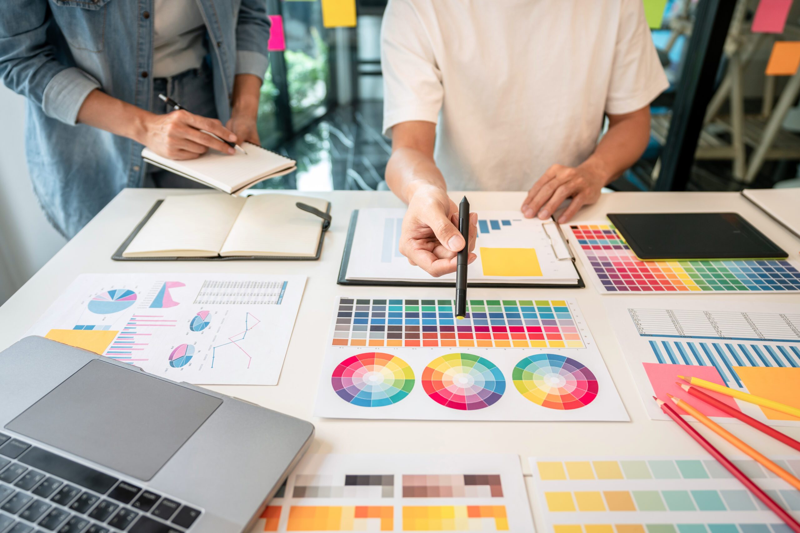 Ein Team kreativer Grafikdesigner arbeitet an einem Farbmusterauswahl-Katalog, um Farben auszuwählen und sich von ihnen inspirieren zu lassen, um eine neue Kollektion am Arbeitsplatz zu erstellen.