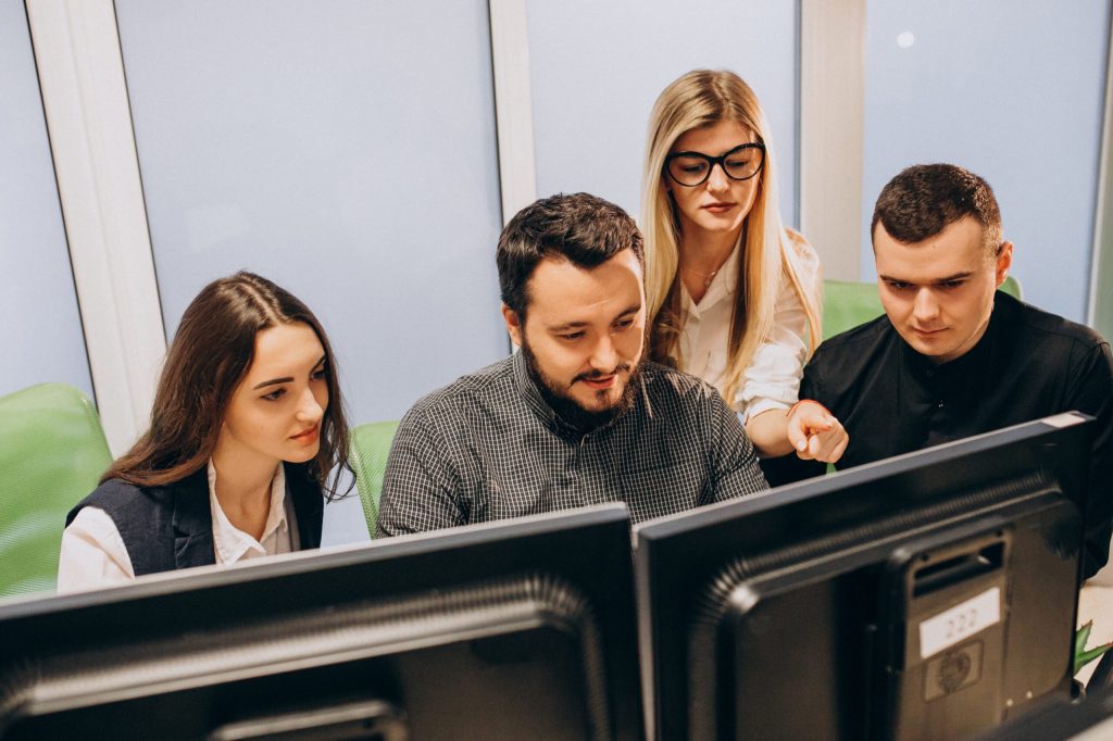 Mitarbeiter eines IT-Unternehmens arbeiten an einem Computer.
