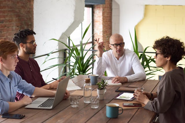 Teamdiskussion in einem modernen Arbeitsumfeld, dargestellt auf einem offenen, gut beleuchteten Bürohintergrund, passend zum Thema 'Kollaboration und Innovation am Arbeitsplatz'.