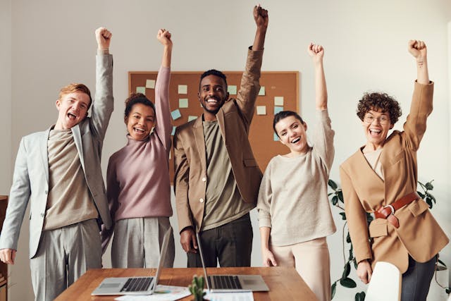 Ein glückliches und produktives Team, unterstützt durch klare Kommunikation, dargestellt vor einem dynamischen Arbeitsumfeld, passend zu einer erfolgreichen Unternehmenskultur.
