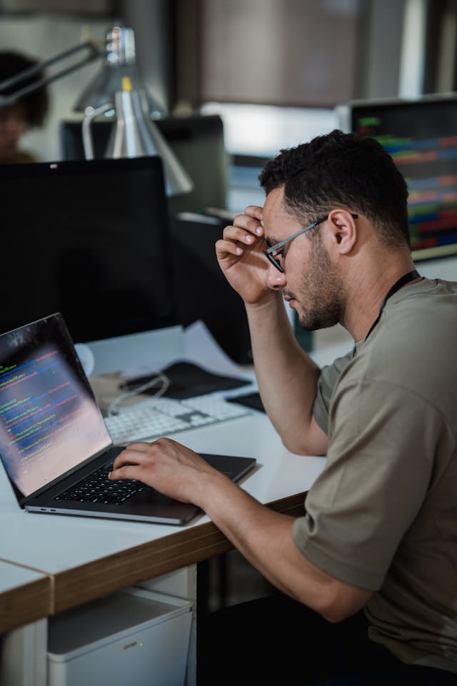 Ein Mann arbeitet konzentriert an einem Computer, in einem modernen und gut organisierten Arbeitsumfeld, das Produktivität und Fokus fördert.